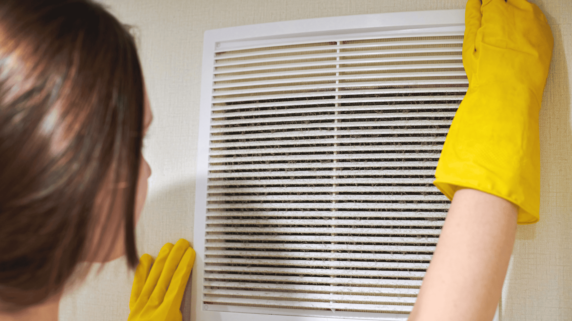 a person wearing yellow gloves is changing an HVAC filter