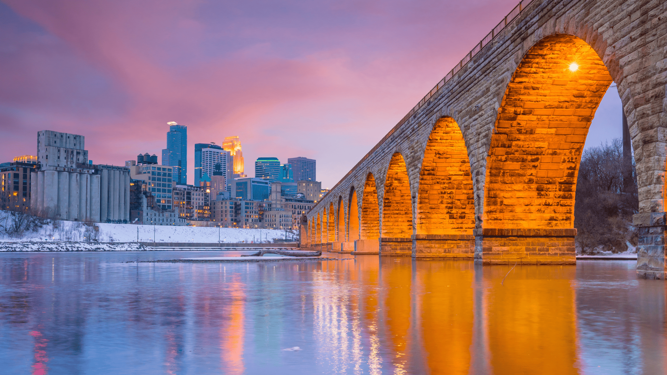 the minneapolis skyline is reflected in the water under an old stone bridge