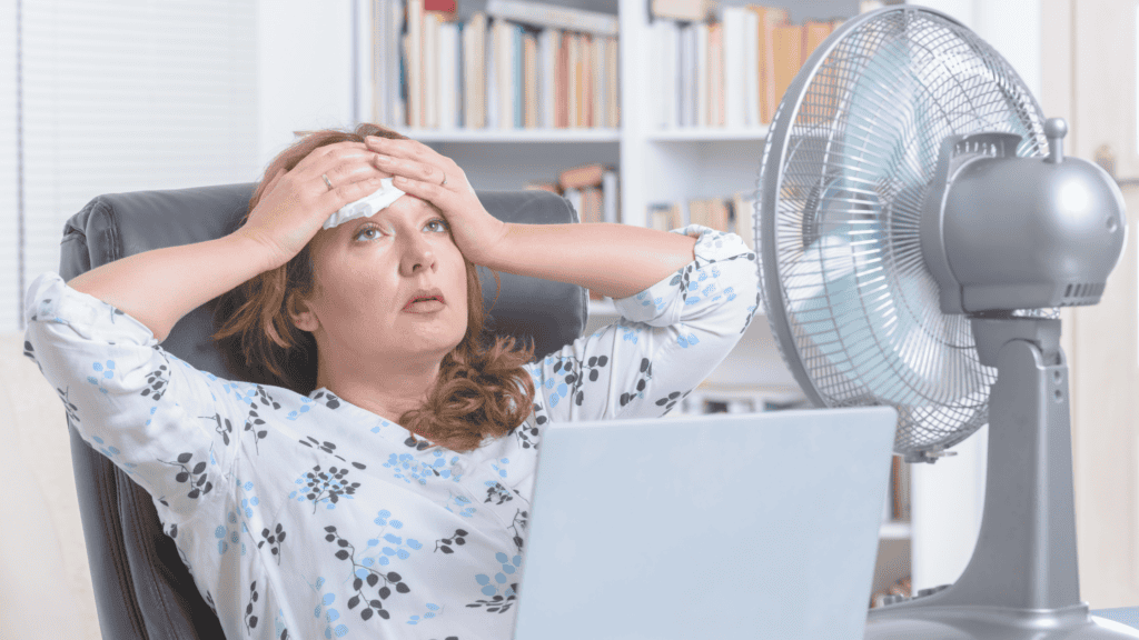 a person sitting in front of a laptop with a fan blowing on their face